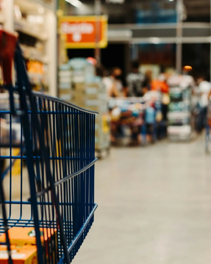 A blue metal shopping cart in a blurred grocery store aisle
