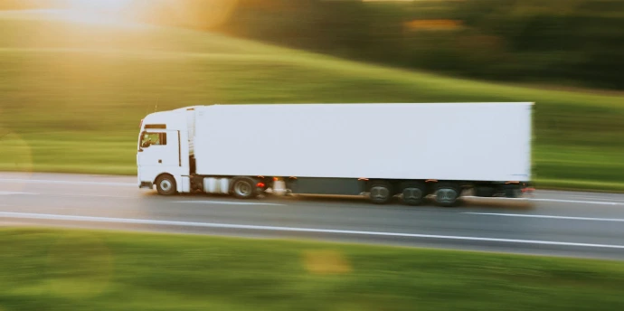 a white semi truck driving down a rural road
